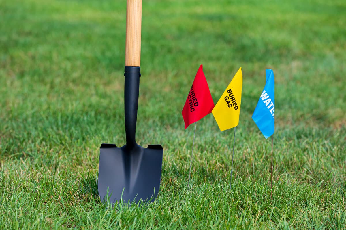 digging w Photo of a shovel in the grass with utility flags